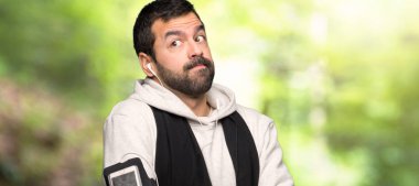 Bir parkta omuzları kaldırarak spor adam şüphe jest yapma