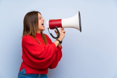 Bir megafon üzerinden bağıran izole mavi duvar üzerinde genç kadın