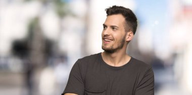 Siyah gömlek ile adam mutlu ve açık havada gülümsüyor