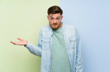 Rengarenk arka plan üzerinde Redhead adam şüpheler jest yapma