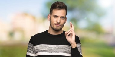 Yakışıklı adam açık havada en iyi dilek ve geçiş parmak ile