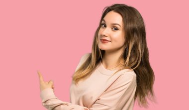 Pembe kazak ile genç kız izole pembe arka plan üzerinde geri işaret