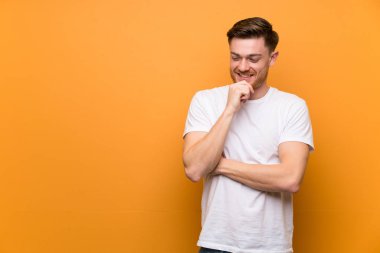 Kırmızı saçlı adam kahverengi duvarın üzerinde yan bakıyor