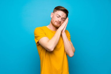 Mavi duvar üzerinde Redhead adam dorable ifade uyku jestyapma