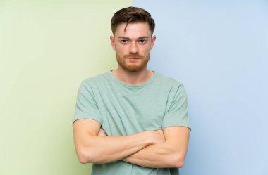 Renkli arka plan üzerinde Redhead adam kollarını çapraz tutmak