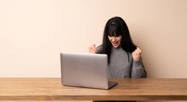 Dizüstü bilgisayarıyla çalışan genç bir kadın galibiyeti kutluyor.