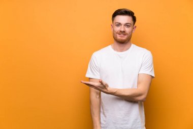 Kahverengi duvar üzerinde Redhead adam doğru gülümseyerek bakarken bir fikir sunan