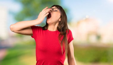 Gözlük esneme ve açık havada elle geniş açık ağız kapsayan kadın