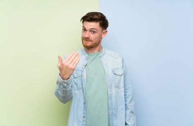 Renkli arka plan üzerinde Redhead adam el ile gelmeye davet ediyor. Geldiğin için mutluyum.