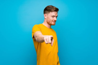 Mavi duvar üzerinde Redhead adam kendine güvenen bir ifade ile size parmak