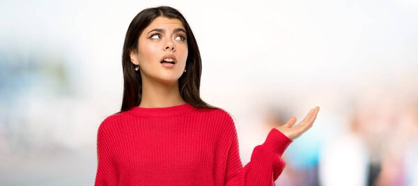 Teenager girl with red sweater unhappy because not understand something at outdoors