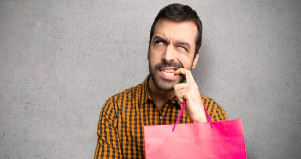 Man Met Boodschappentassen Met Twijfels Tijdens Het Opzoeken Textuur Muur — Stockfoto