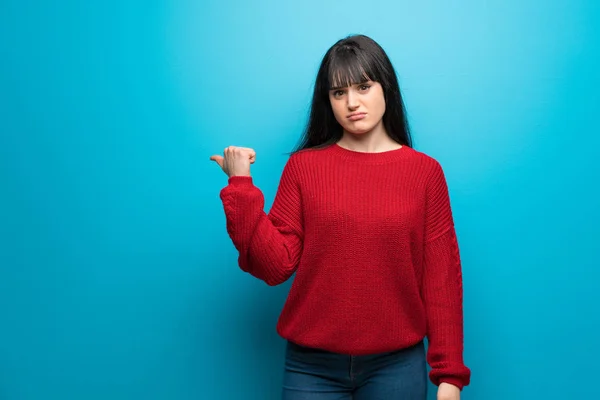 Mujer Con Suéter Rojo Sobre Pared Azul Infeliz Apuntando Hacia — Foto de Stock