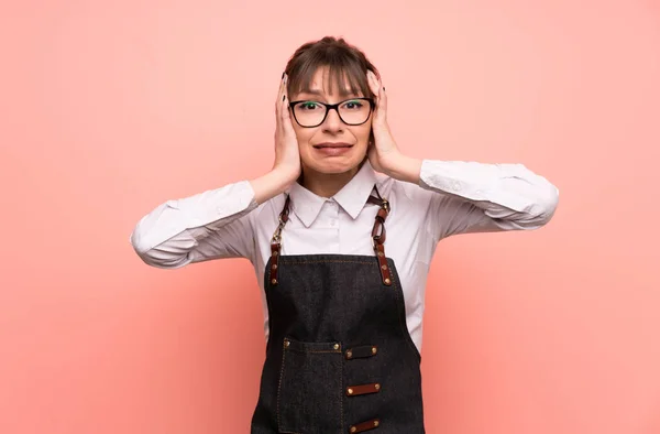 Young waitress over pink background with surprise facial expression