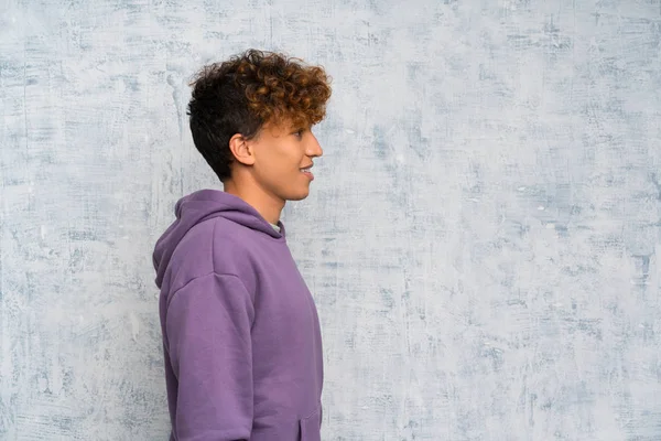 Genç afro-amerikan adam grunge duvar üzerinde ayakta ve yan bakıyor