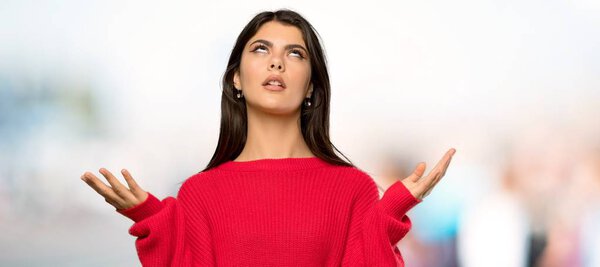 Teenager girl with red sweater frustrated by a bad situation at outdoors