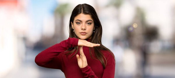 Teenager girl with turtleneck making time out gesture at outdoors