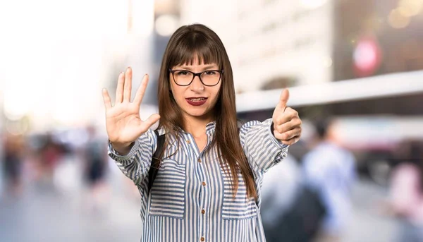 Woman with glasses counting six with fingers at outdoors
