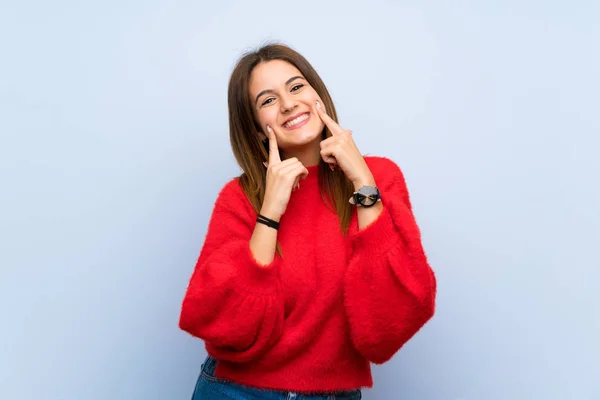 Young woman over isolated blue wall smiling with a happy and pleasant expression