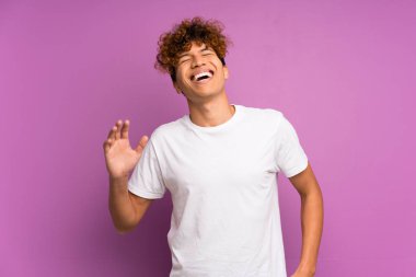İzole edilmiş mor duvarın üzerinde gülümseyen genç bir Afro-Amerikalı.