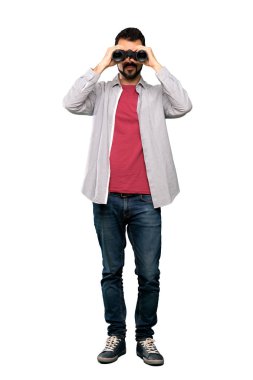 İzole beyaz arka plan üzerinde dürbün ile sakallı yakışıklı adam tam uzunlukta atış