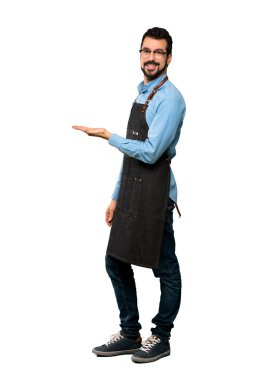 Tam uzunlukta çekim adam apron ile izole beyaz arka plan üzerine karşı gülümseyen görünümlü bir fikir sunma