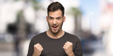 Siyah gömlek ile adam açık havada kazanan pozisyonda bir zafer kutluyor