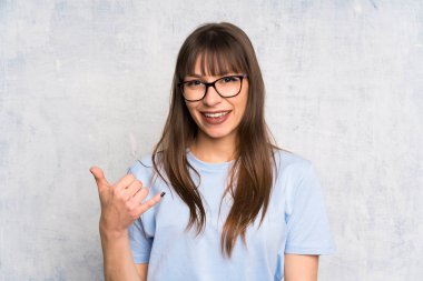 Grunge geçmişli genç bir kadın telefon jesti yapıyor.