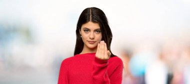 El ile gelmek için davet kırmızı kazak ile genç kız. Açık havada geldiğiniz için mutlu