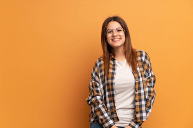 Gözlük ve mutlu ile kahverengi duvar üzerinde genç kadın