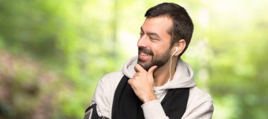 Spor adam bir parkta çene el ile tarafa bakıyor