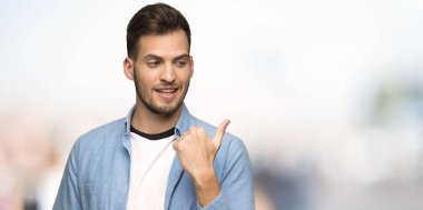 Açık havada ürün sunmak için yakışıklı erkek tarafına işaret