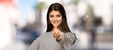 Açık havada bir parmak gösteren ve kaldırma çizgili gömlek ile genç kız