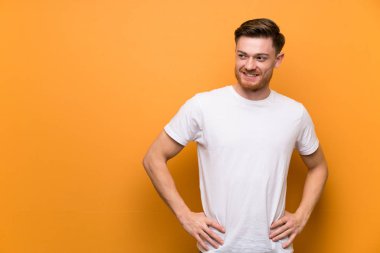 Kahverengi duvar üzerinde Redhead adam kalça kolları ile poz ve gülümseyerek