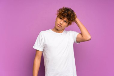 Genç Afro-Amerikalı adam, mor duvarın üstünde, kafasını kaşıyıp kuşkulanırken