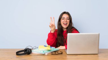 Genç öğrenci kız bir tablo gülümseyen ve zafer işareti gösteren okuyan