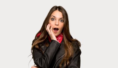 Deri ceket ile genç kadın sürpriz ve izole gri arka plan üzerinde doğru bakarak şok