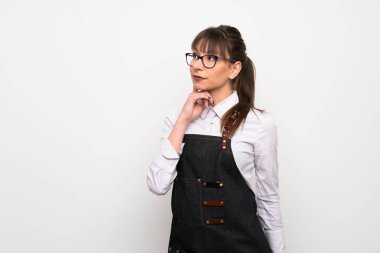 Önlüklü genç kadın yukarı bakarken bir fikir düşünüyor.