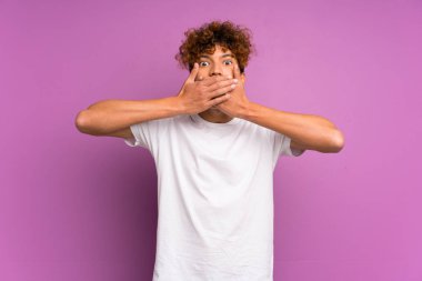 Elleri ile ağız kapsayan izole mor duvar üzerinde Genç Afrikalı Amerikalı adam