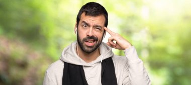 Spor adam bir parkta kafasına parmak koyarak delilik jest yapma