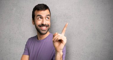 Yakışıklı adam harika bir fikir işaret ve dokulu duvar üzerinde bakıyor