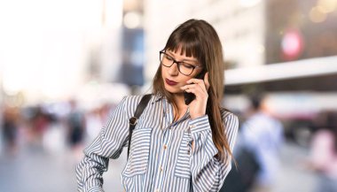 Açık havada cep telefonu ile sohbet tutan gözlük kadın