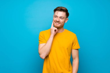 Mavi duvar üzerinde Redhead adam bakarken bir fikir düşünüyor