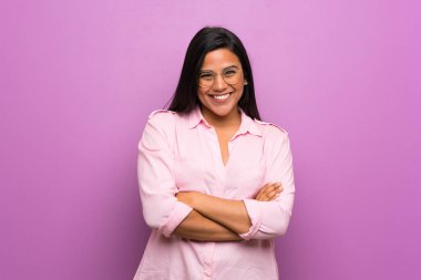 Mor duvarın üzerinden gözlüklü ve mutlu genç Kolombiyalı kız.