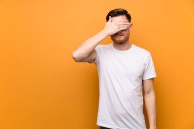 Kahverengi duvarın üzerinde gözleri elleriyle kaplayan kızıl saçlı adam. Bir şey görmek istemiyorum