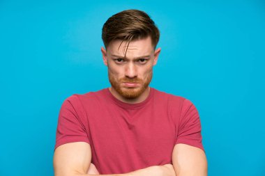Izole mavi duvar üzgün redhead adam