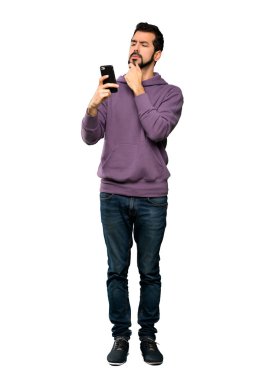 Sweatshirt düşünme ve izole beyaz arka plan üzerinde bir mesaj göndererek yakışıklı adam tam uzunlukta çekim