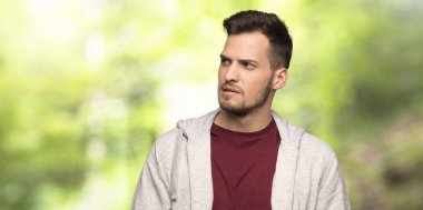 Bir parkta ısırık dudak iken yüz ifadesi karıştırır ile Sweatshirt ile adam