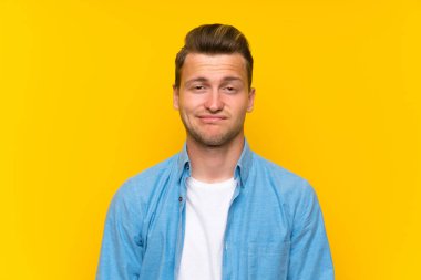 İzole duvar üzerinde sarışın yakışıklı adam şüpheler ve yüz ifadesi ile karıştırmayın