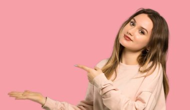 Pembe kazak ile genç kız izole pembe arka plan üzerine bir reklam eklemek için avuç içinde boşaltmak hayali tutan